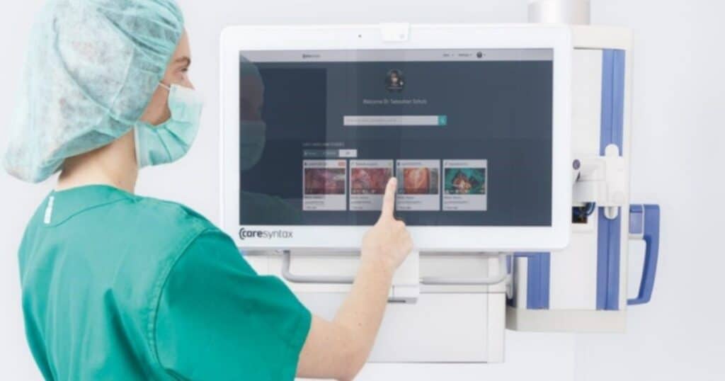 Surgeon stands at computer reviewing surgical recordings.